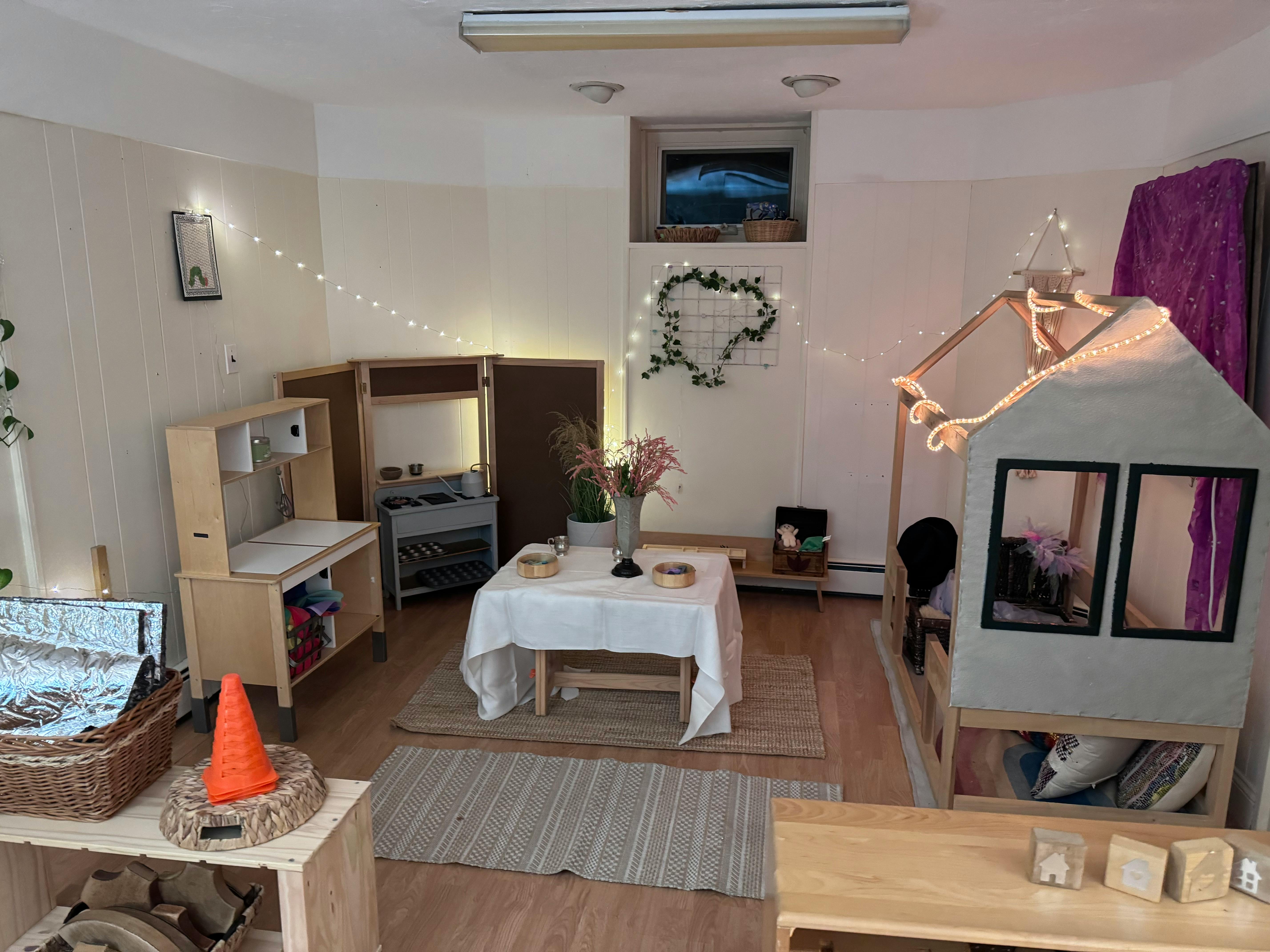 Playroom with a small table, play kitchen, and house-shaped bed frame