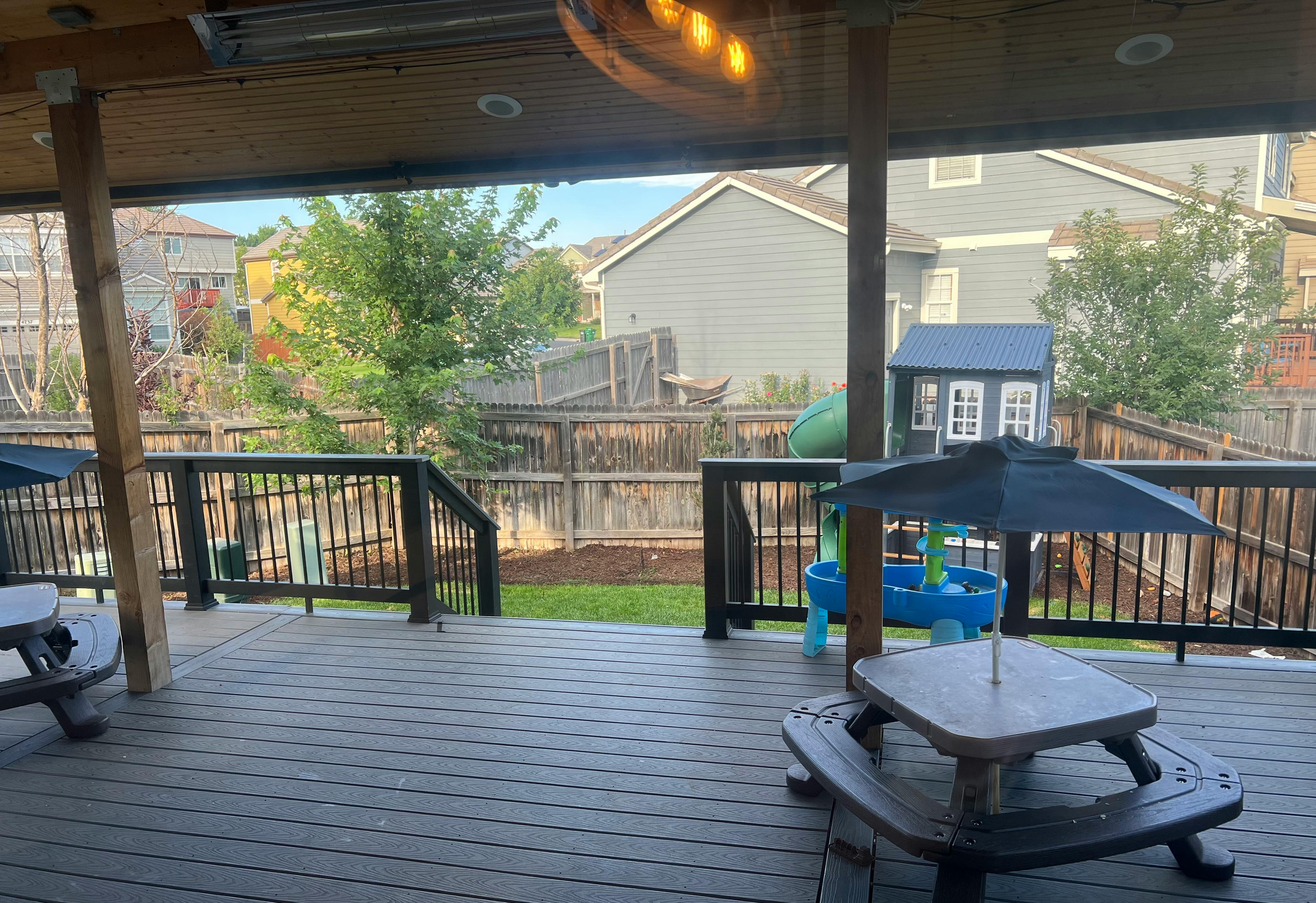 Deck with a small picnic table and umbrella overlooking a backyard