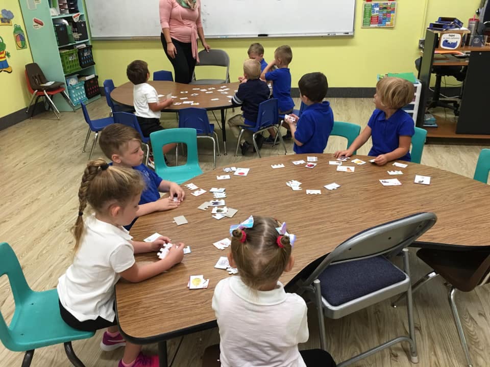 Children sitting at tables in a classroom playing with cards