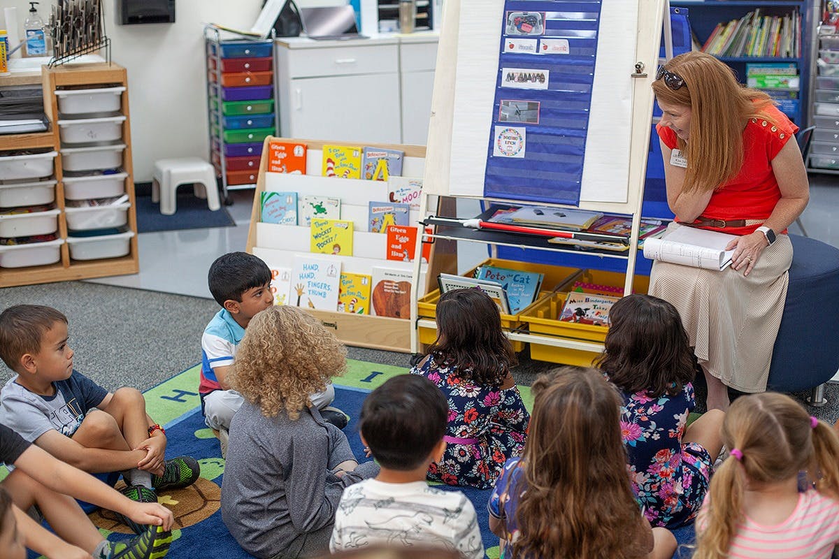 Adult reading to children sitting on a rug in a classroom