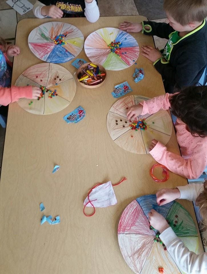 Children decorating paper plates with small colorful objects