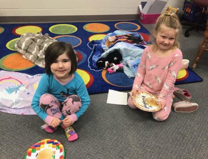 Two children sitting on a rug, one holding a decorated plate