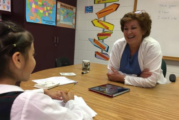 Adult and child sitting at a table in a classroom