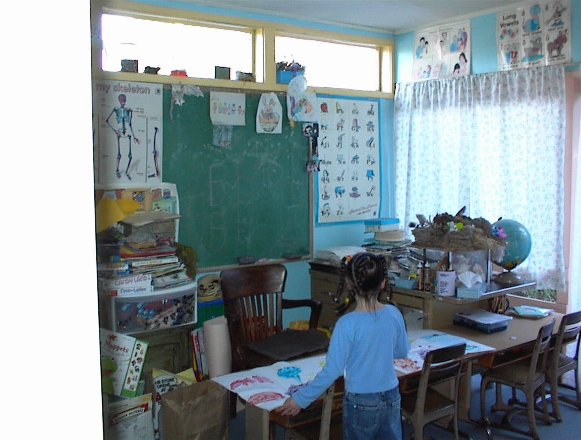 Child standing at a desk in a classroom