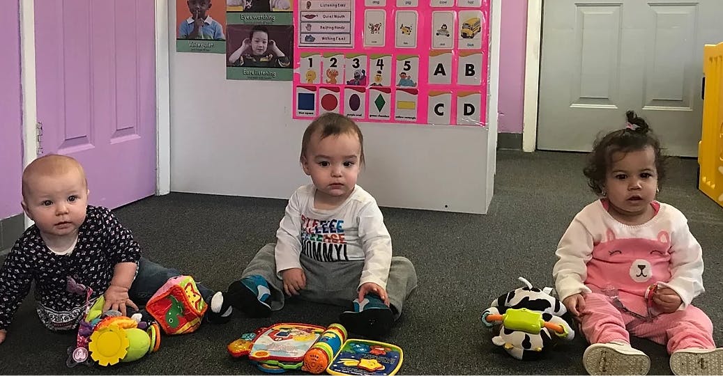 Three babies sitting on the floor with toys