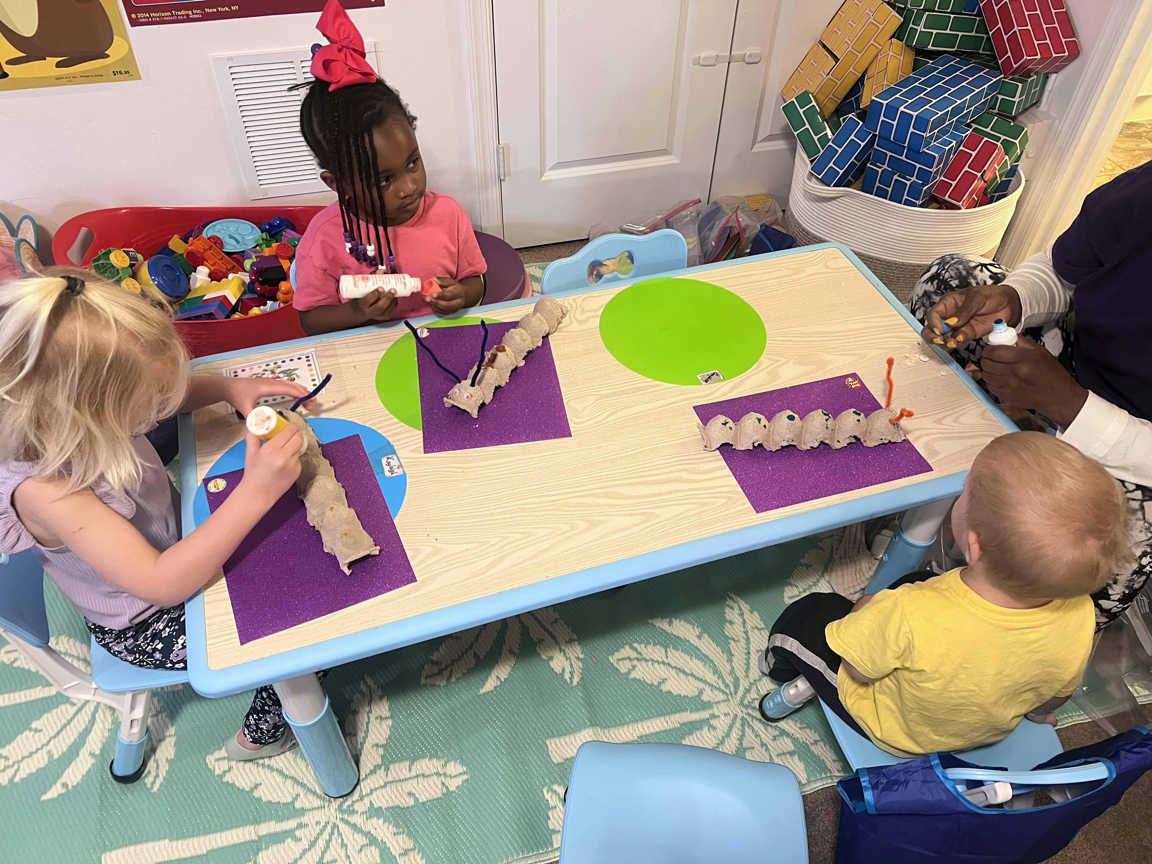 Children doing crafts at a table with adults nearby