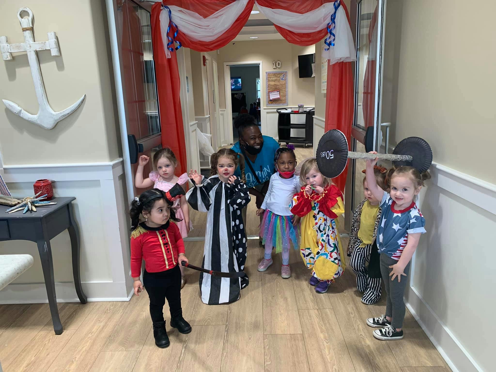 Children in costumes with an adult, one child holding a toy barbell