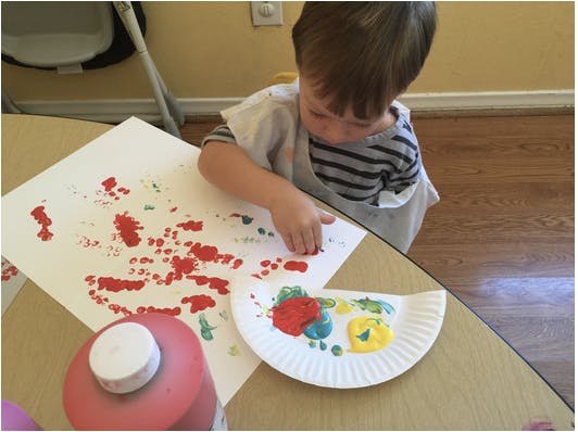 Child finger painting on paper at a table