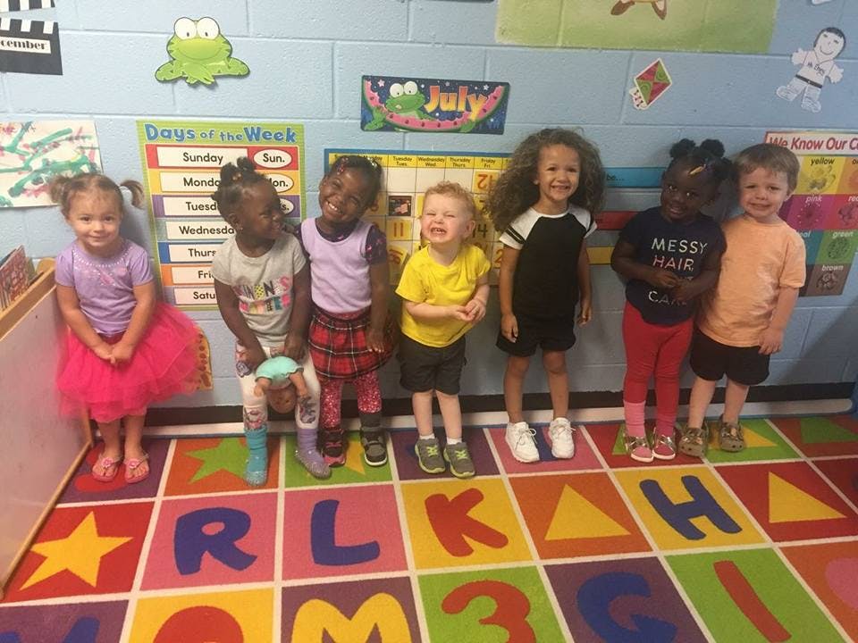 Seven children standing in a classroom