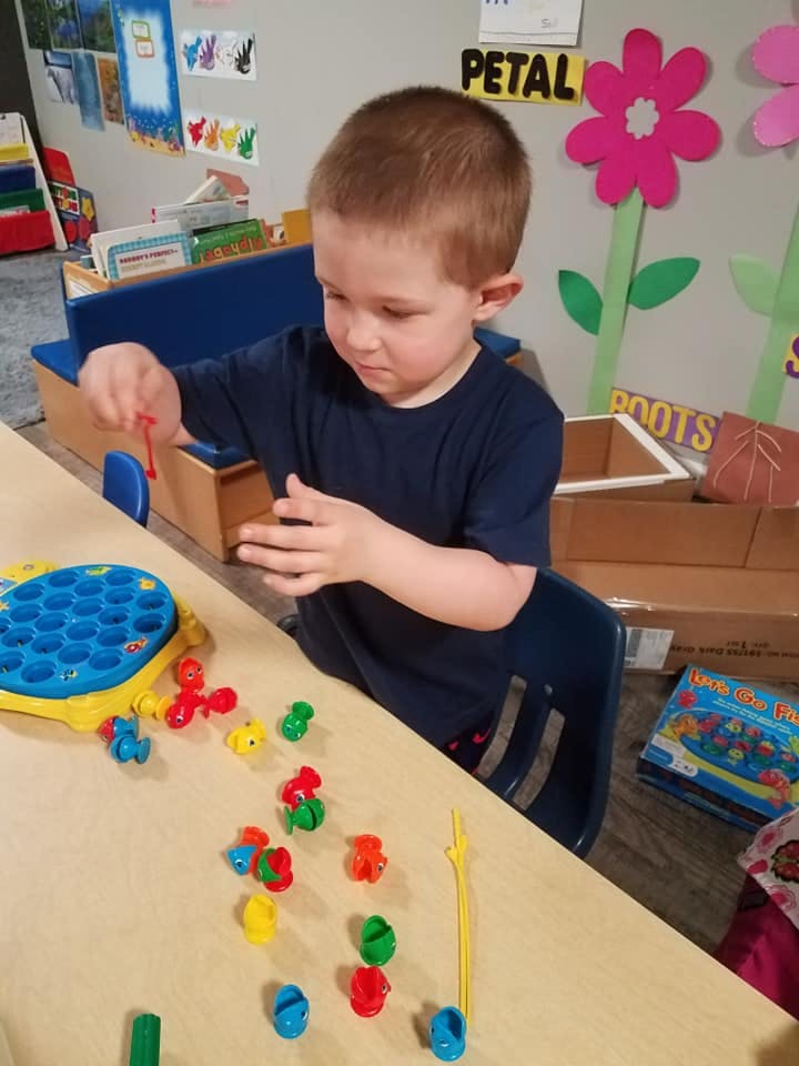 Child playing with a fishing game at a table