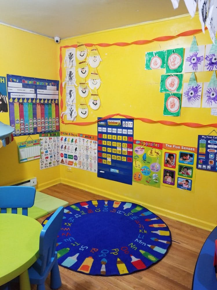 Classroom with yellow walls, colorful charts, and a blue rug