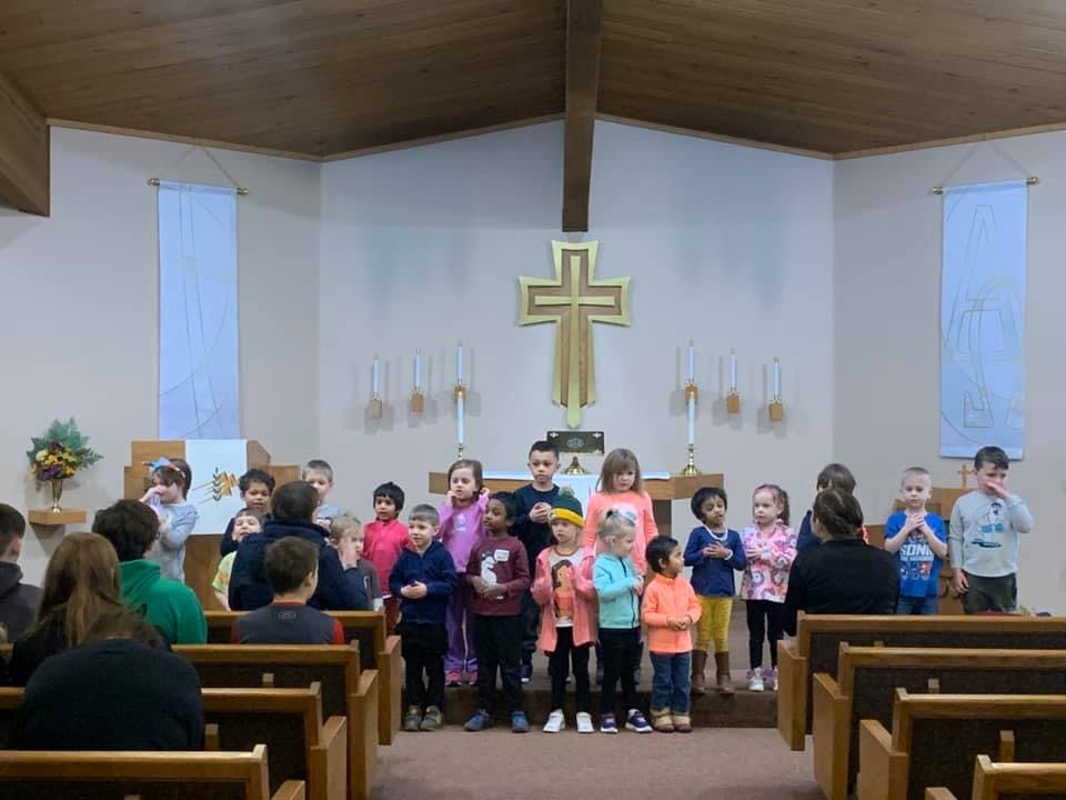 Children standing in front of a cross in a church