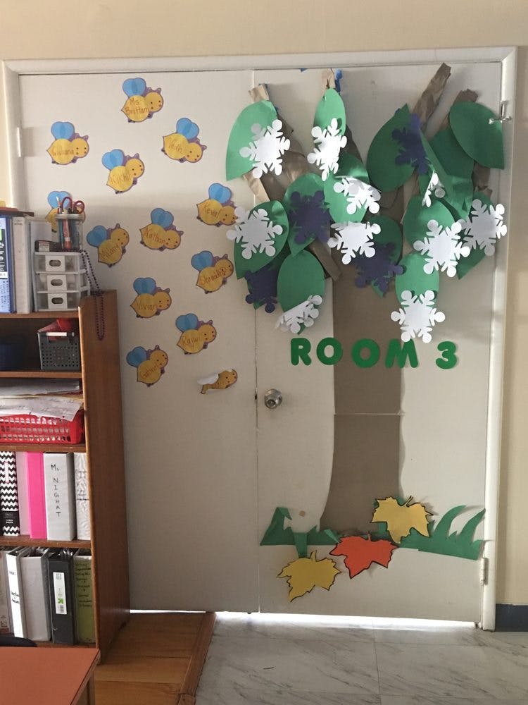 Classroom door decorated with paper cutouts of bees and a tree with snowflakes