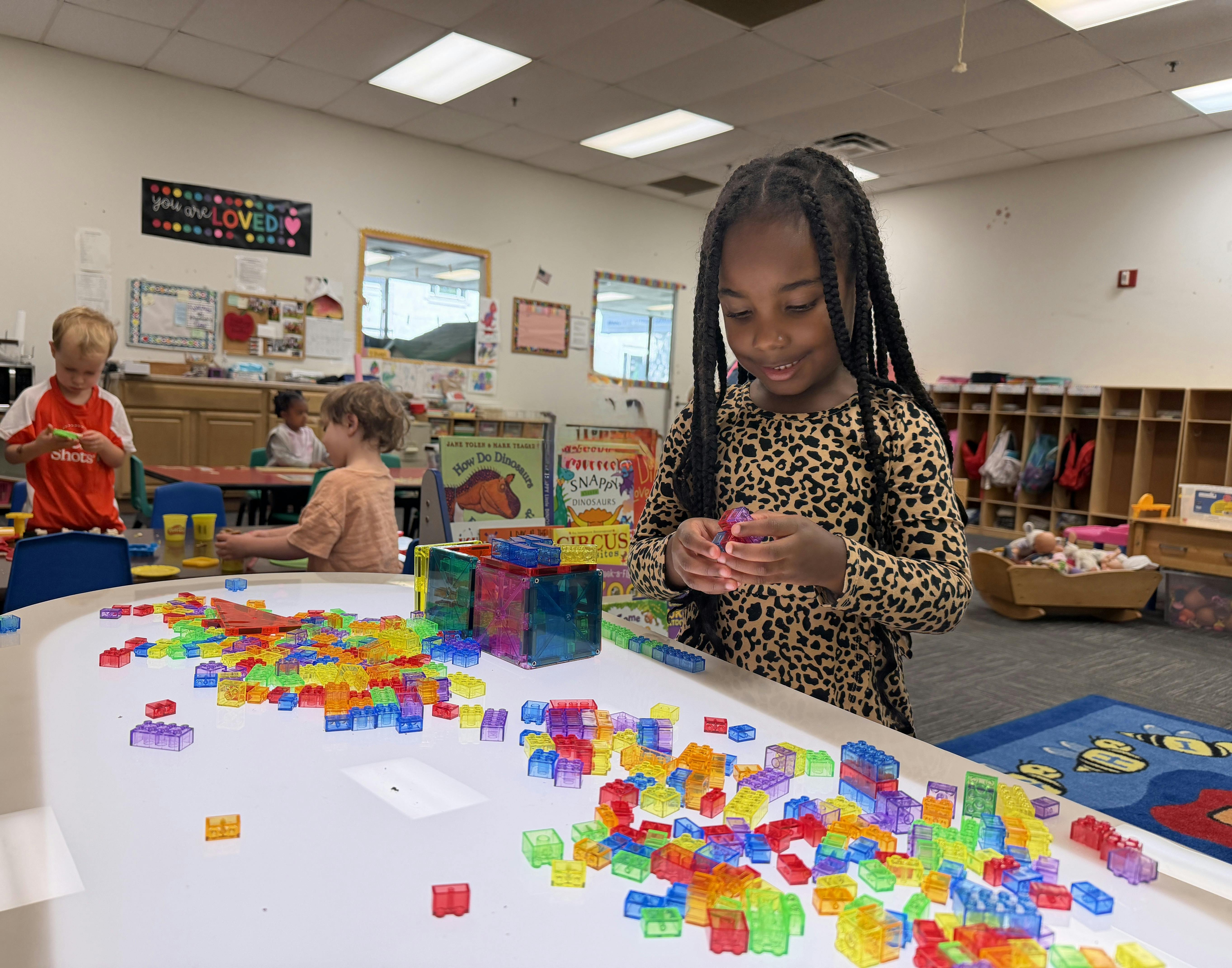 Child building with colorful magnetic blocks at a table in a classroom