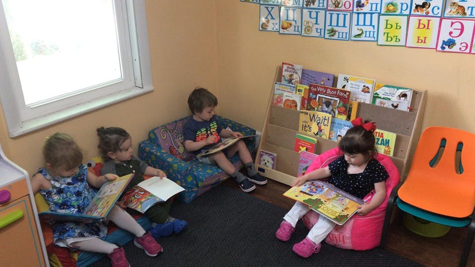 Three children reading books in a classroom