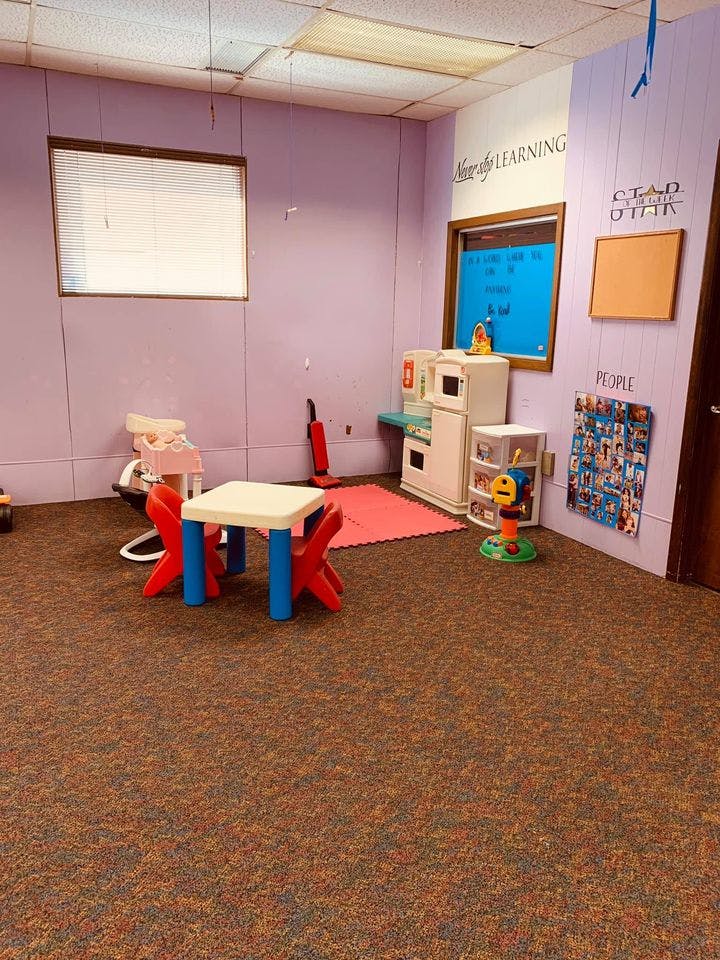 Children's play area with small table and chairs, toy kitchen, and play mat