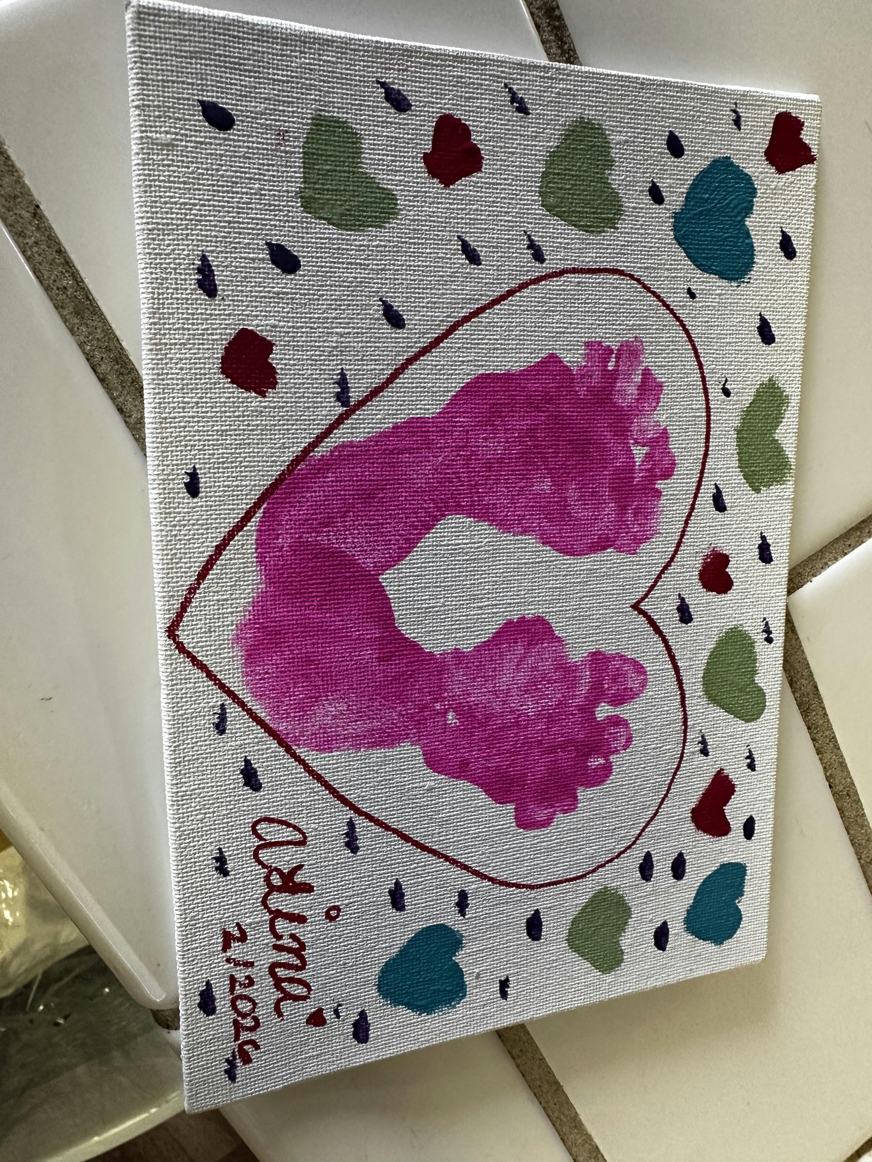 Baby footprints in a heart shape on a white canvas with scattered hearts