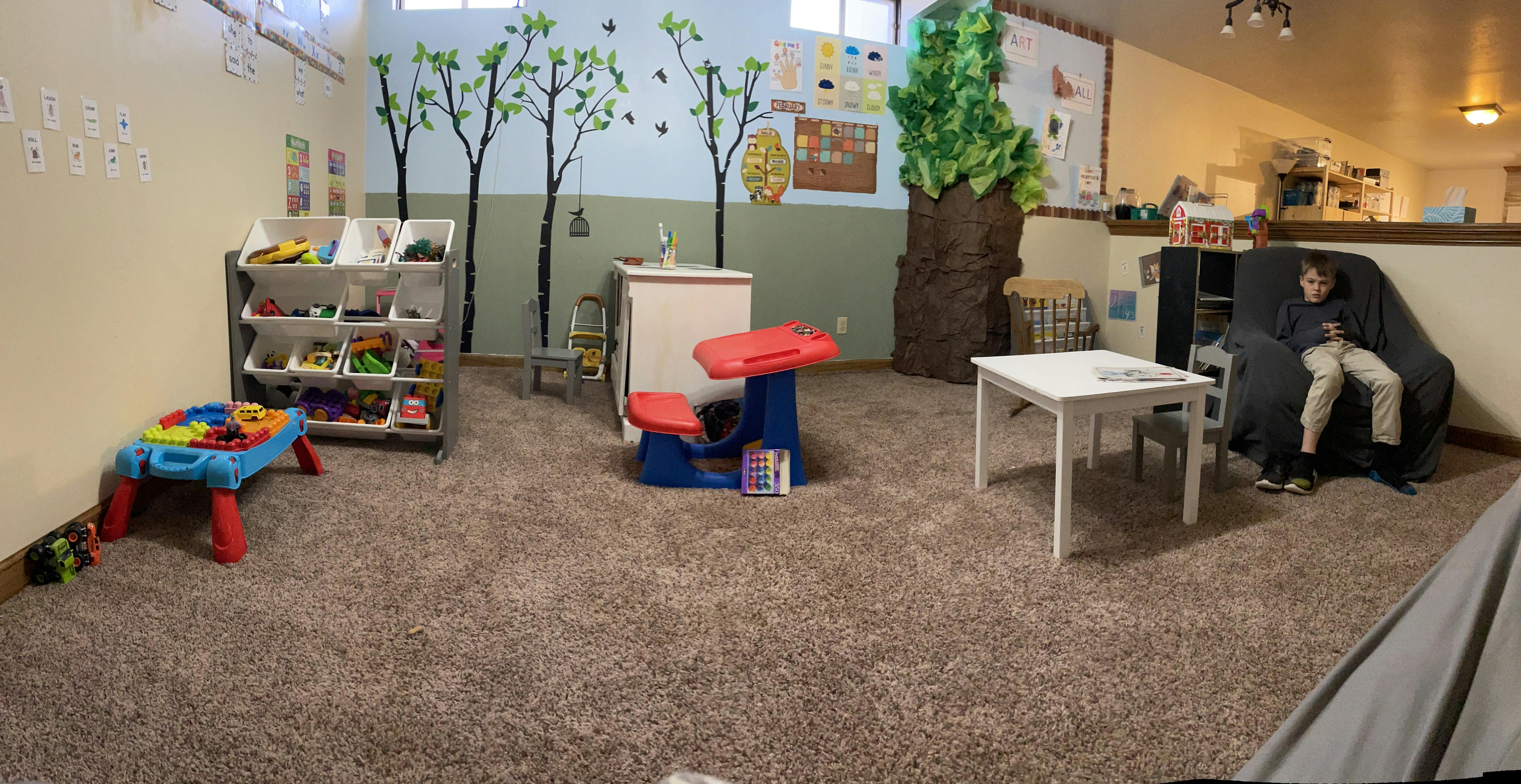 Child sitting on a couch in a playroom with toys and furniture