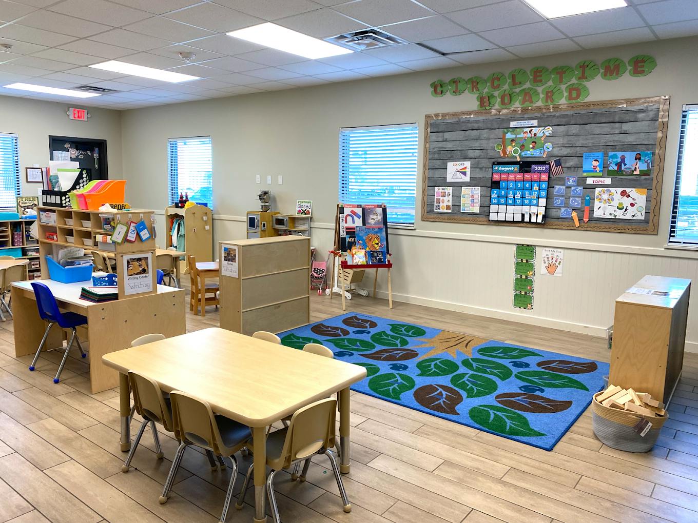 Classroom interior with small tables, chairs, and a circle time display board