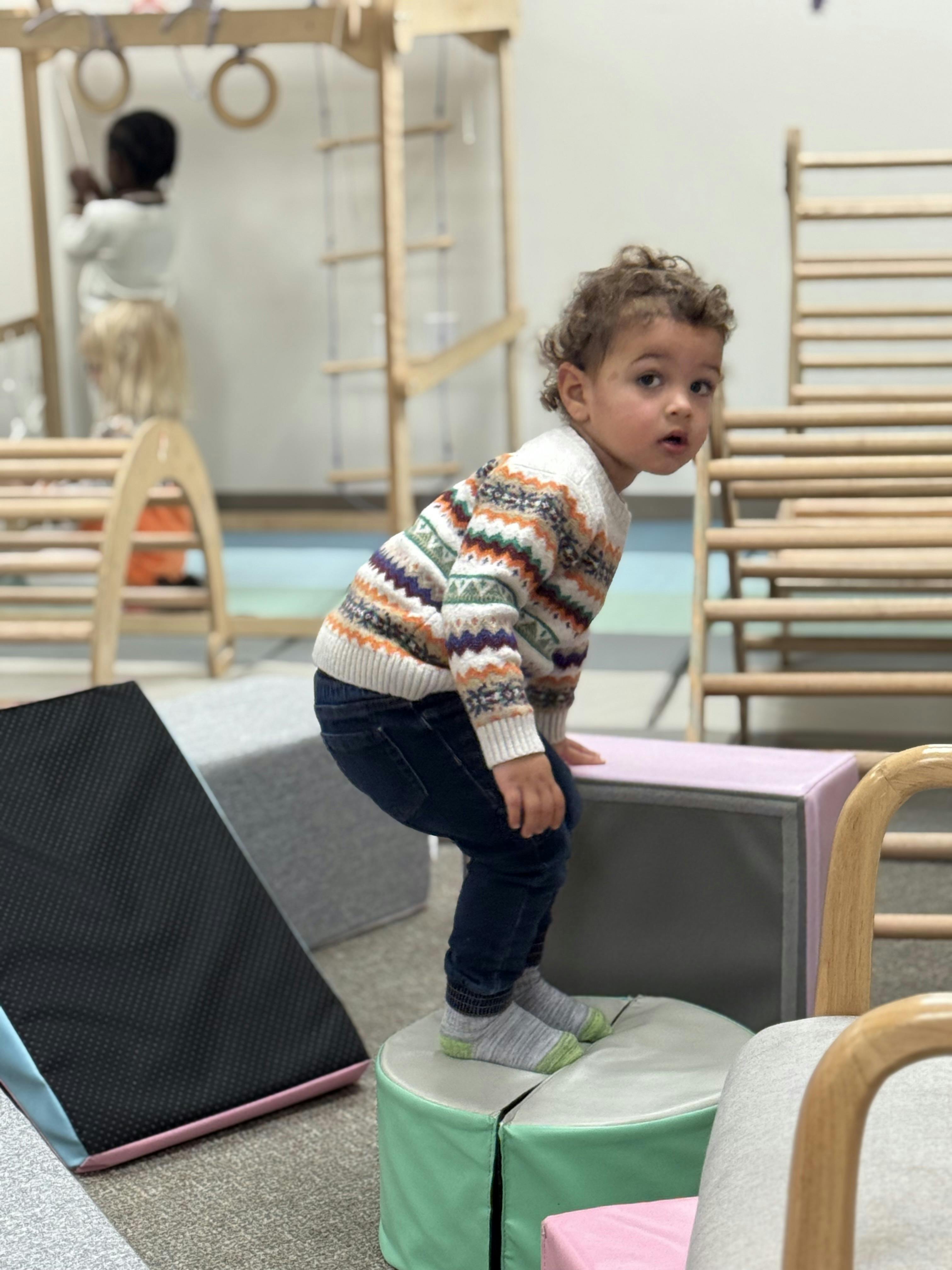 Child standing on foam climbing blocks in a playroom