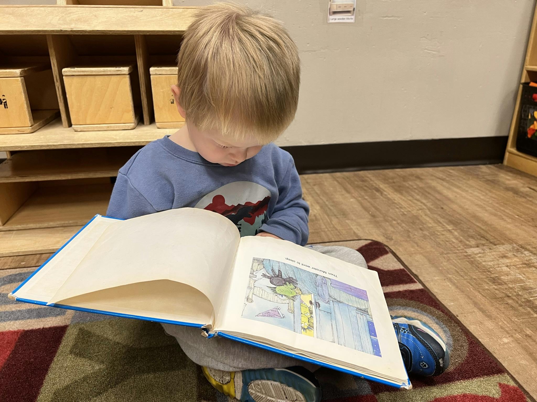 Child sitting on a rug and looking at an open book