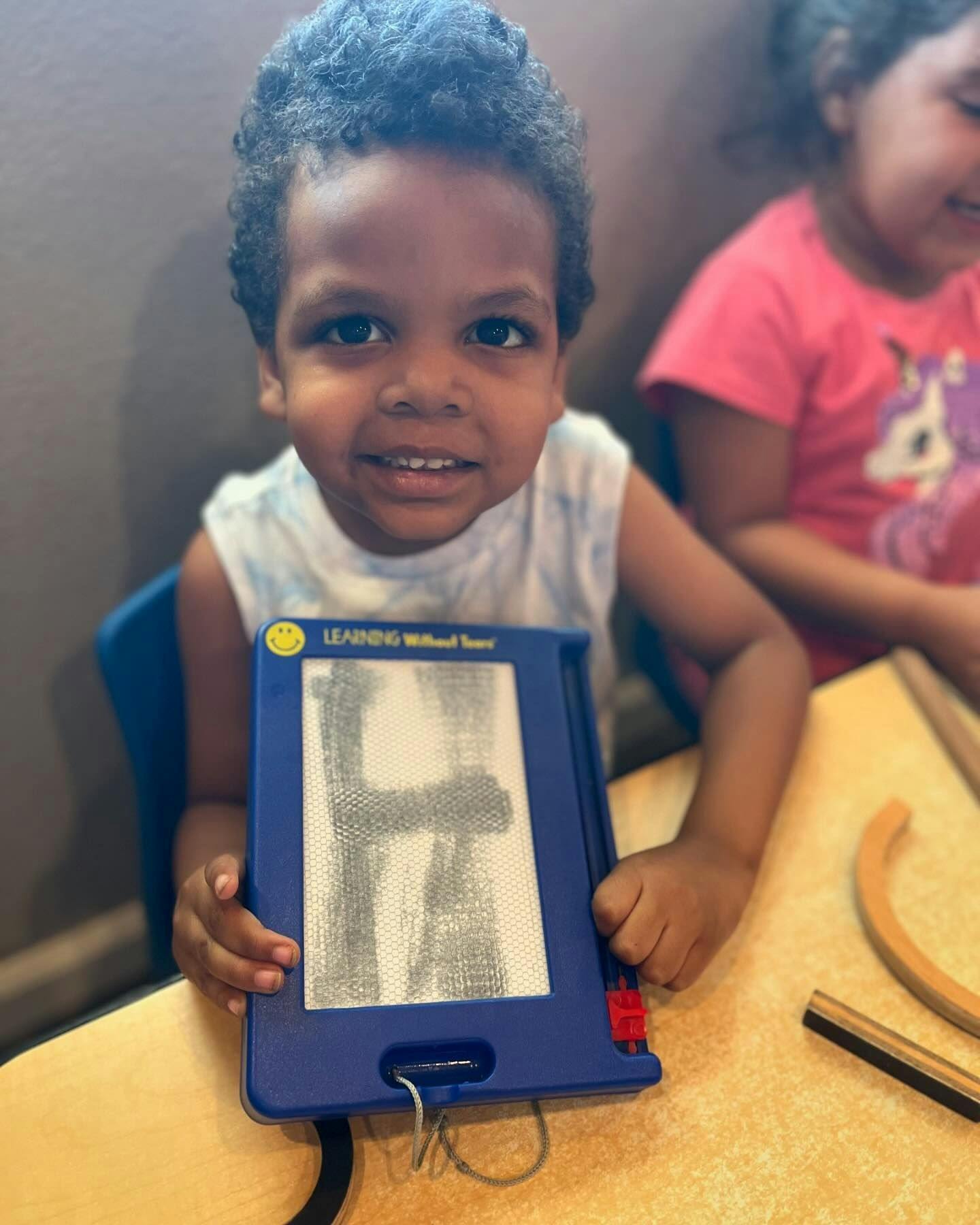 Child holding a Learning Without Tears writing slate