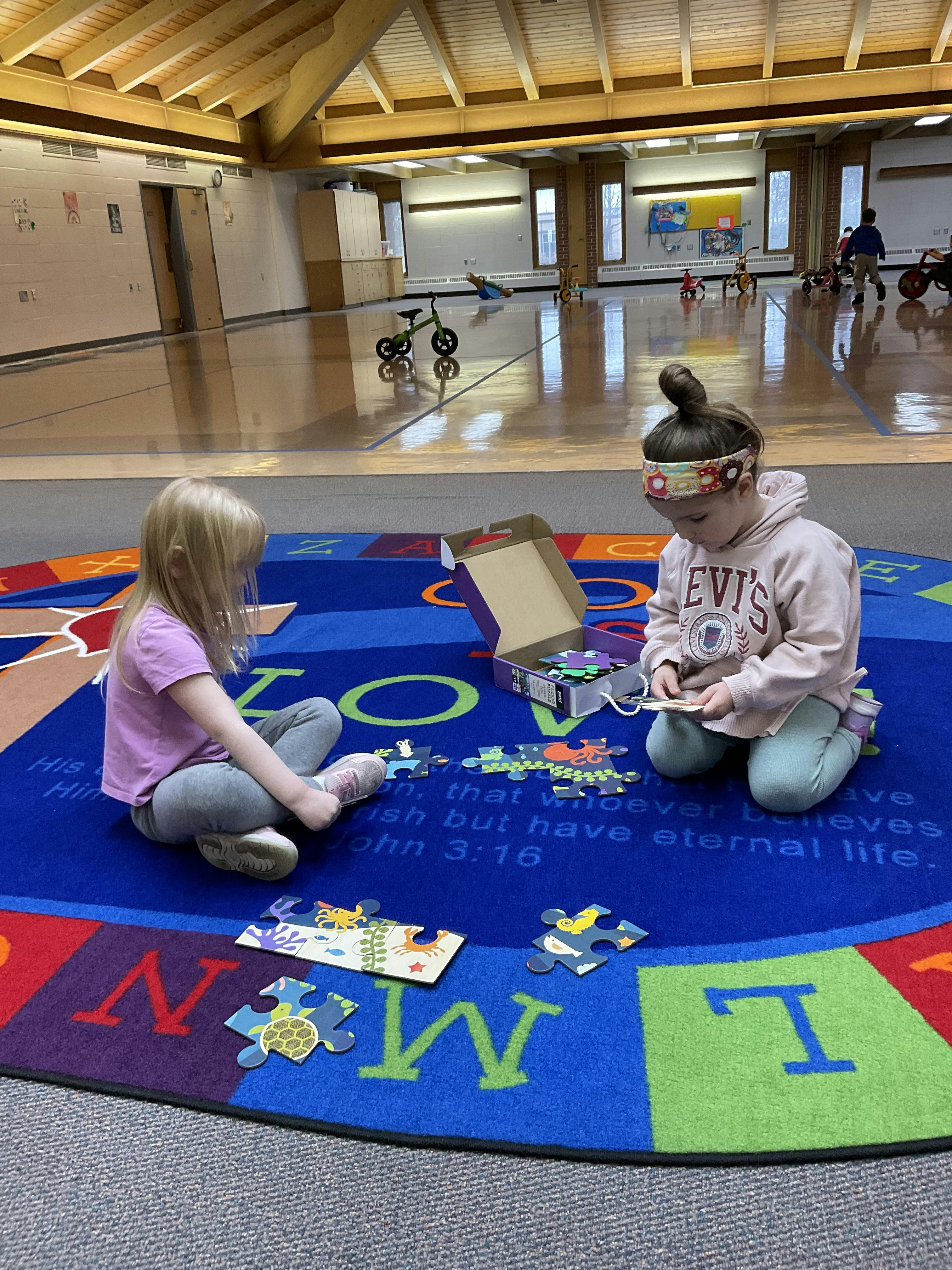 Two children playing with puzzles on a colorful rug