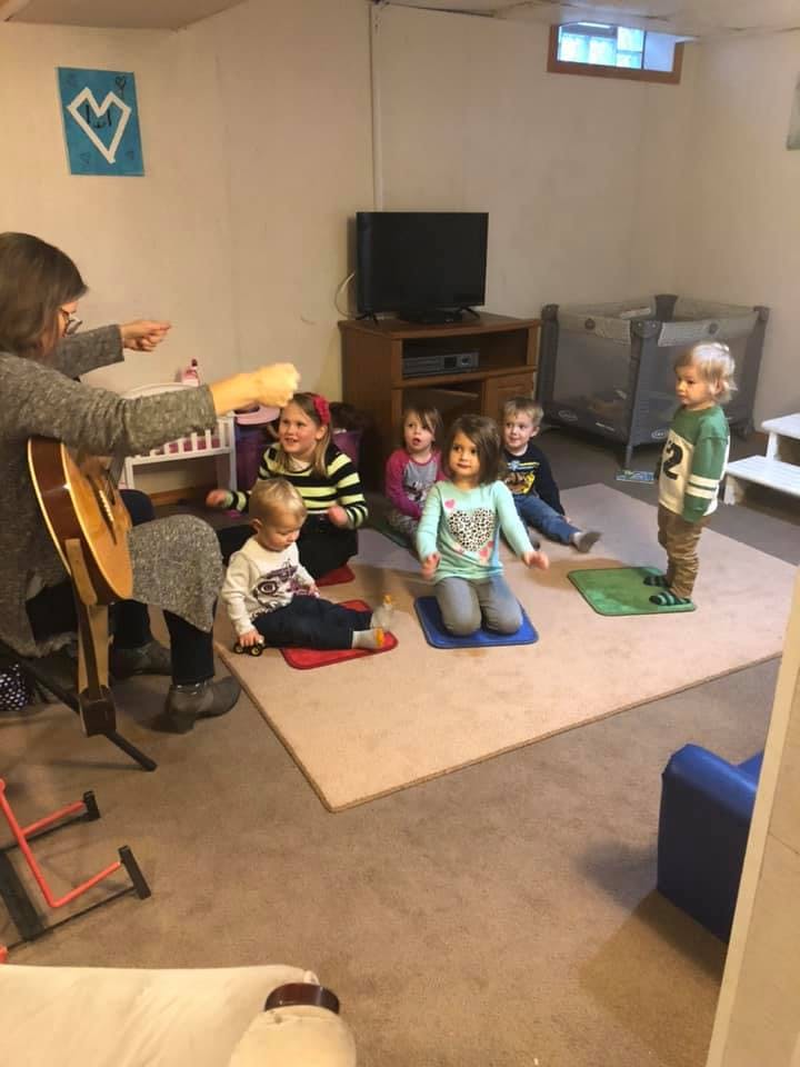 Adult playing guitar for a group of children