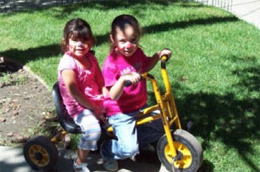 Two children on a yellow tricycle