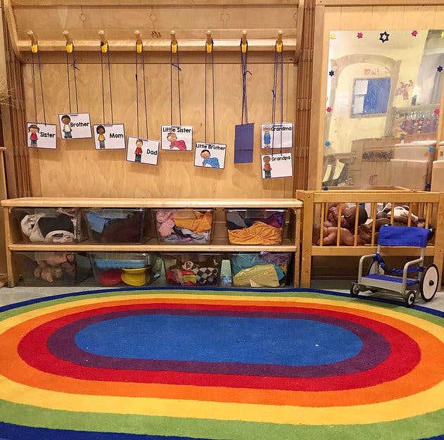 Classroom with a rainbow rug, storage shelves, and a crib