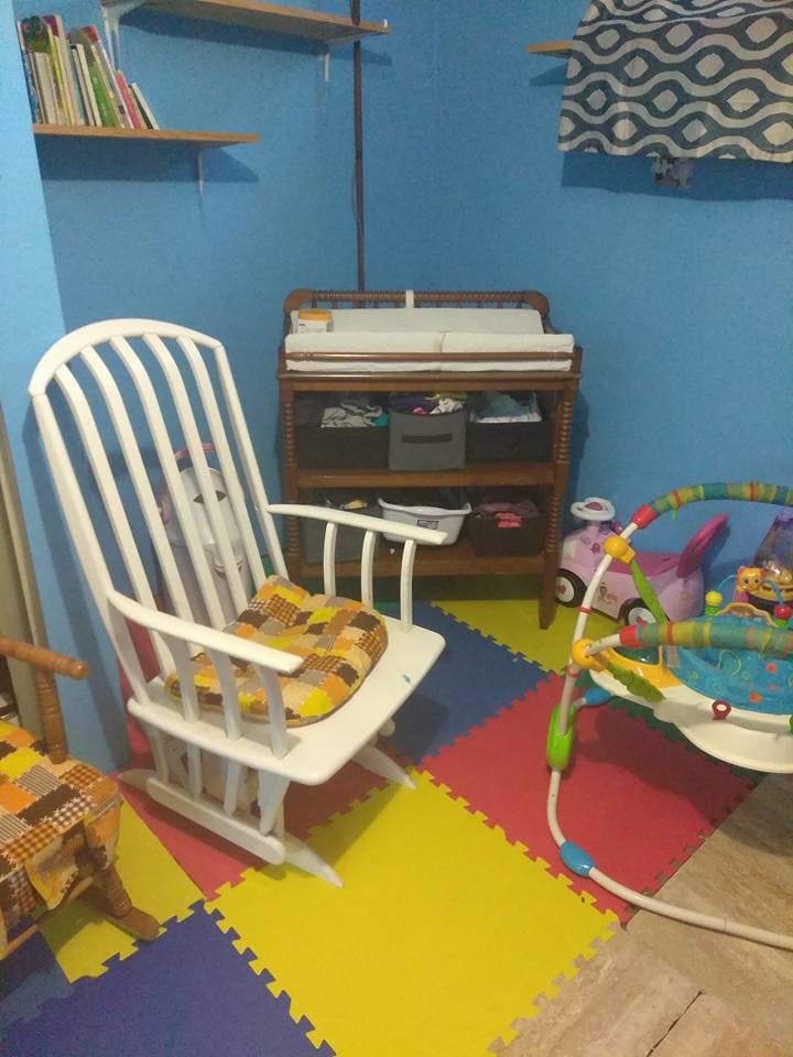 Nursery room with a white rocking chair, changing table, and play mat