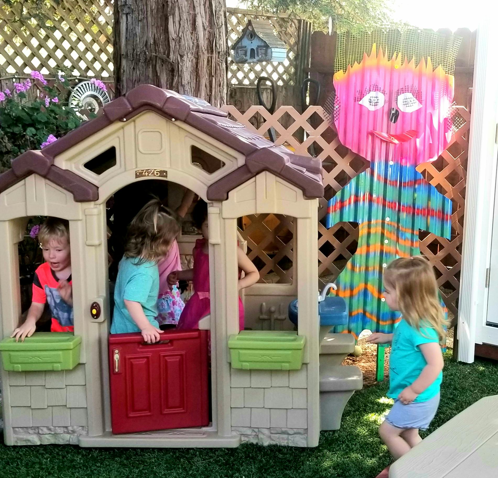 Children playing in and around a small playhouse