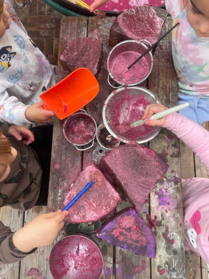 Children playing with paint on a wooden table