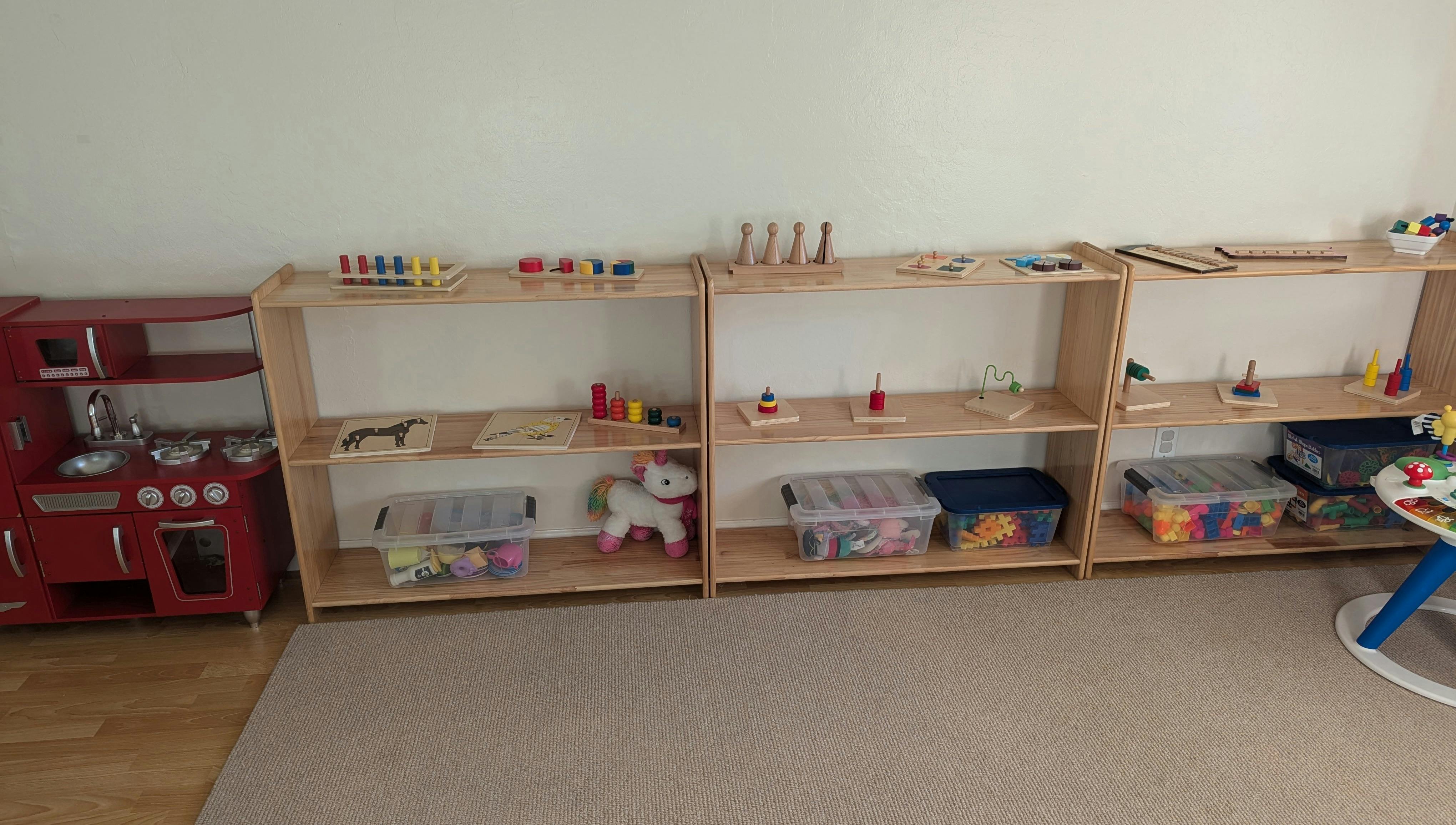 Children's play area with a red toy kitchen and wooden shelving units