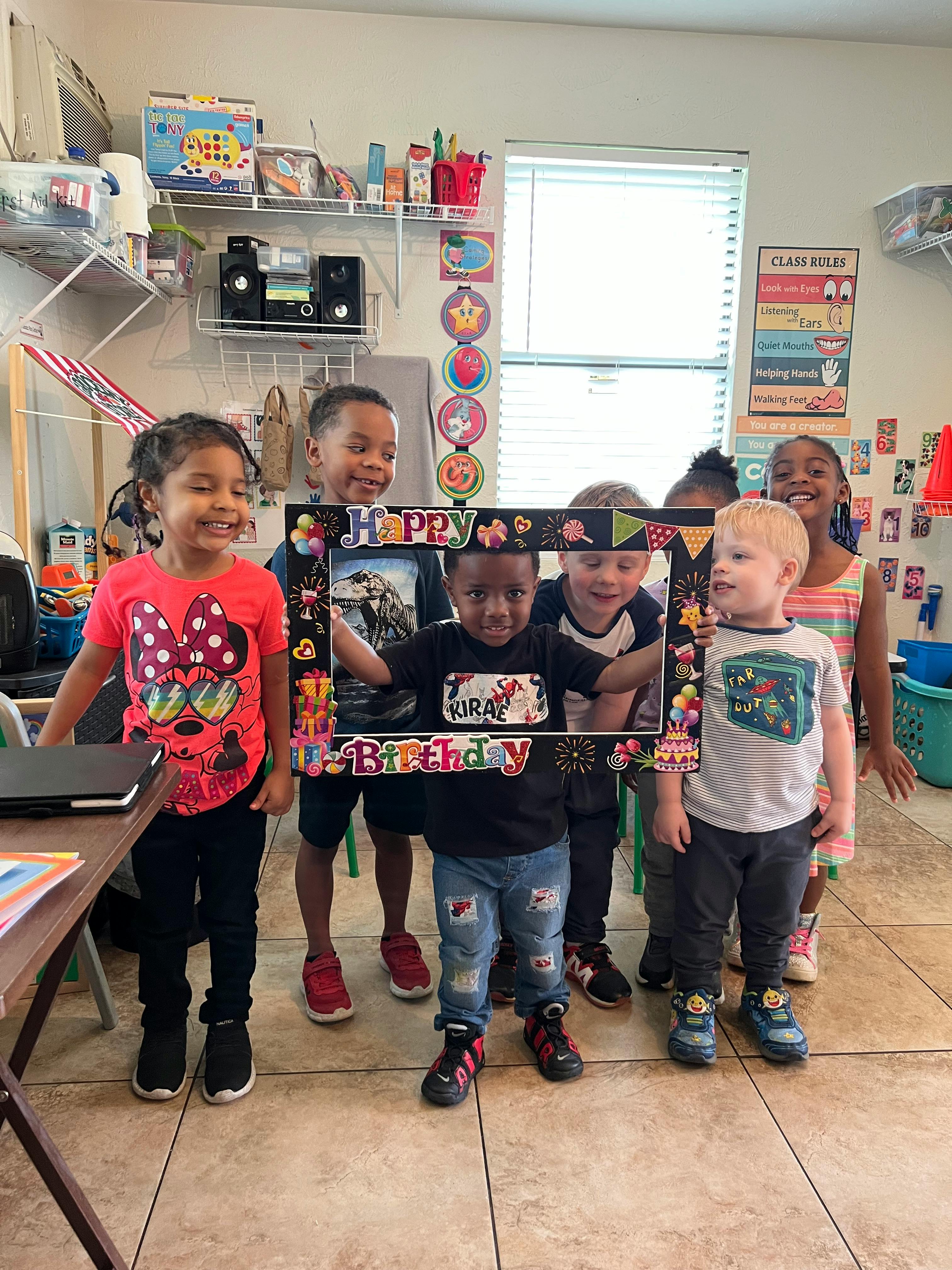 Group of children posing with a Happy Birthday frame
