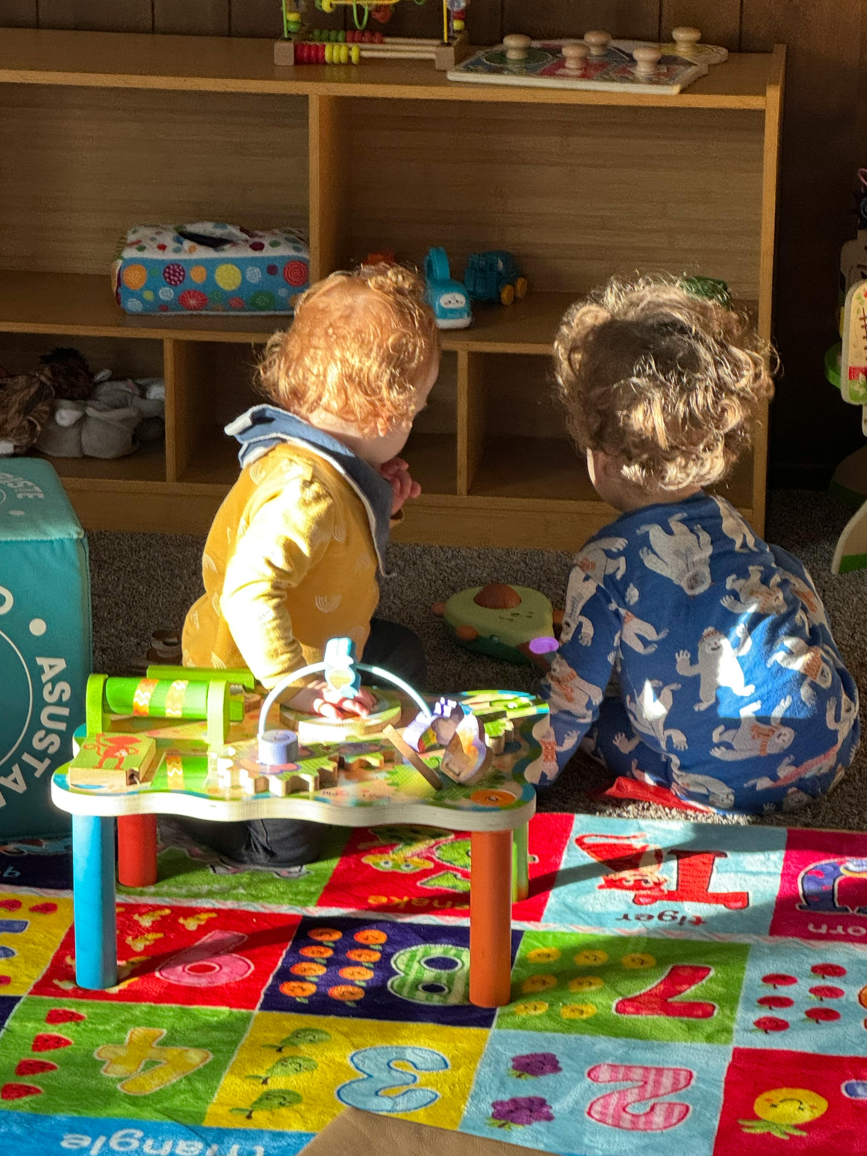 Two children playing with a toy on a colorful number mat