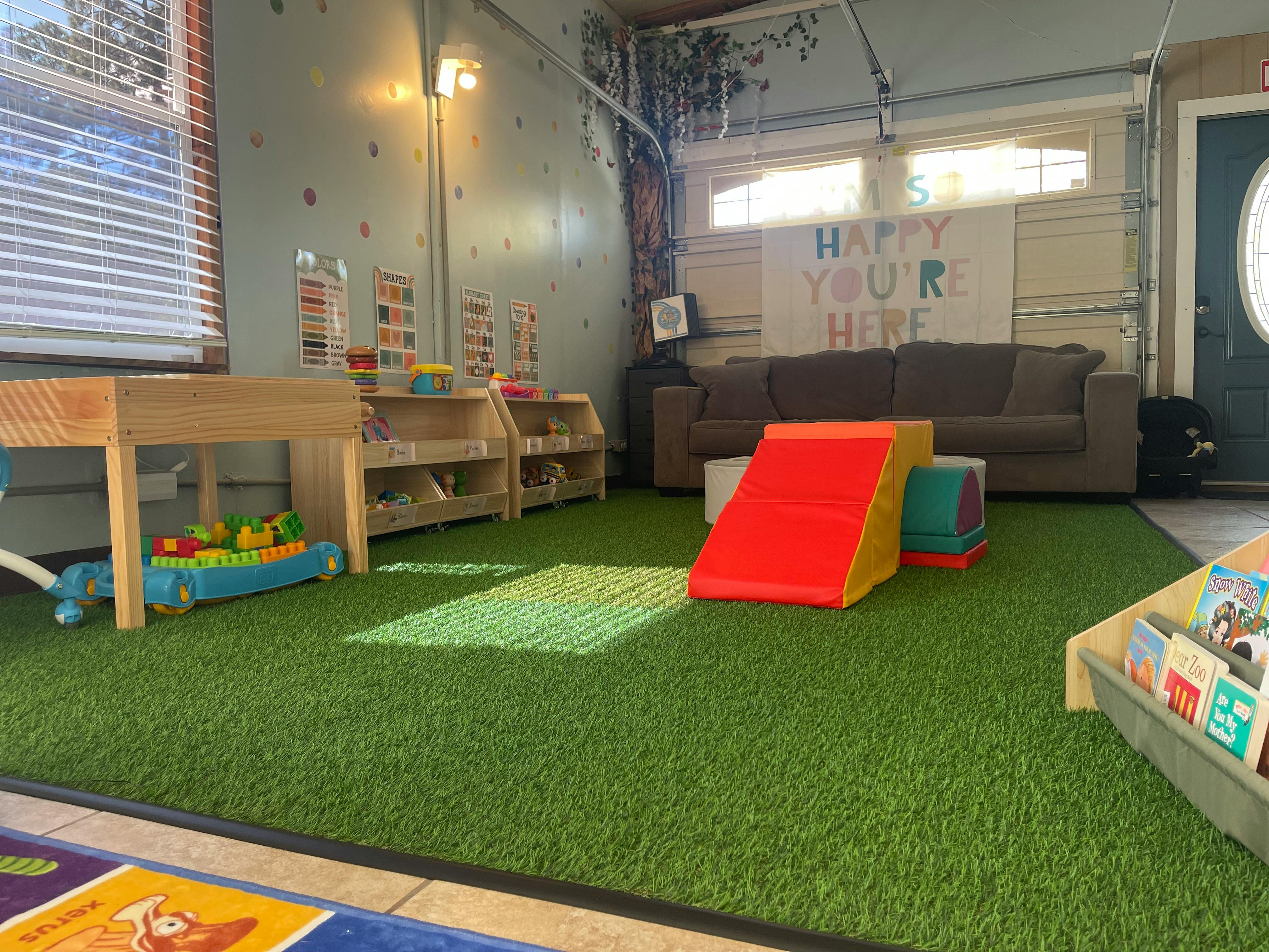 Playroom with artificial grass, climbing foam blocks, and bookshelves