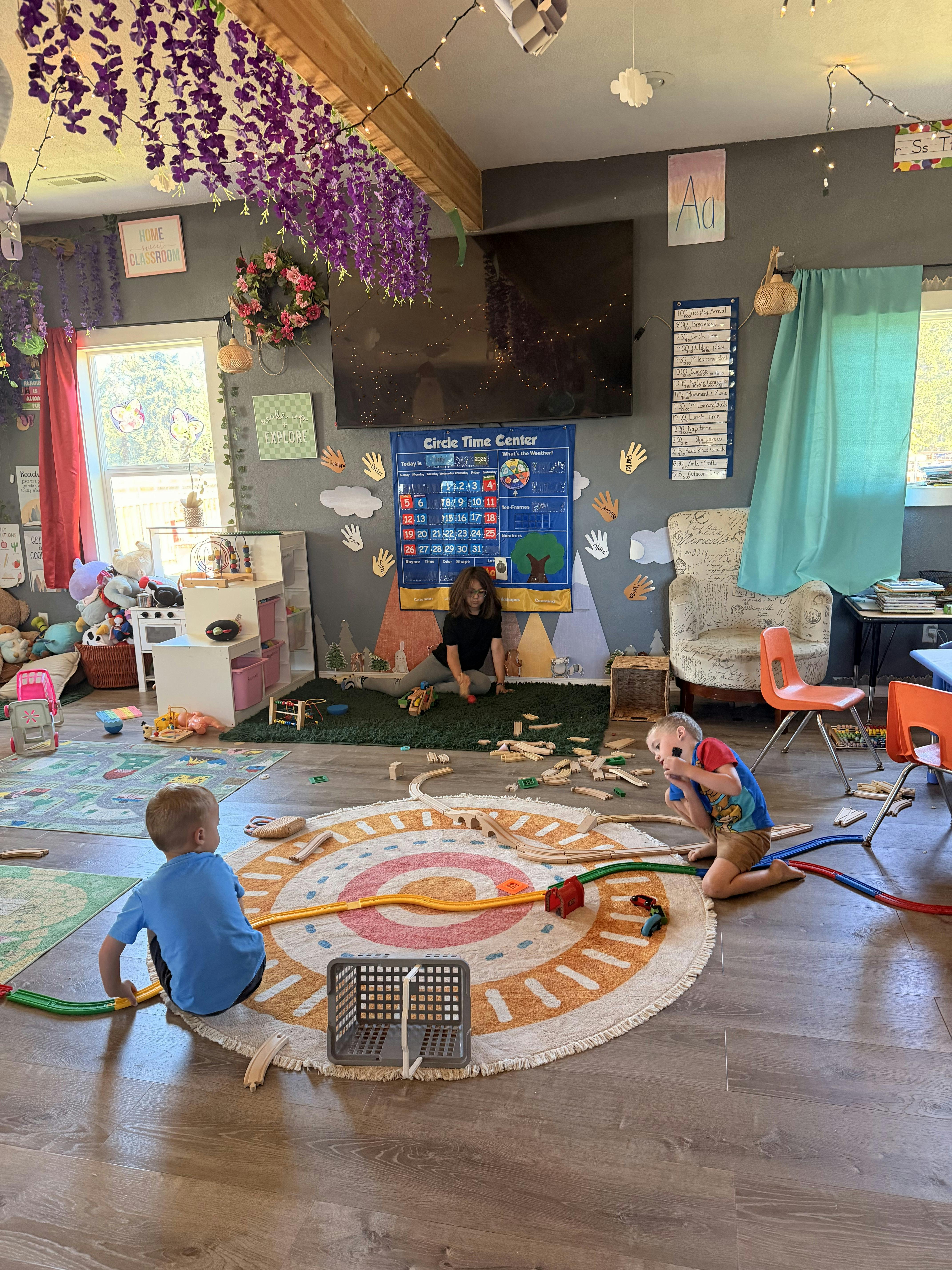 Children playing with train tracks on the floor in a classroom