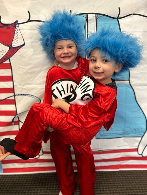 Two children in red Thing 1 and Thing 2 costumes with blue wigs