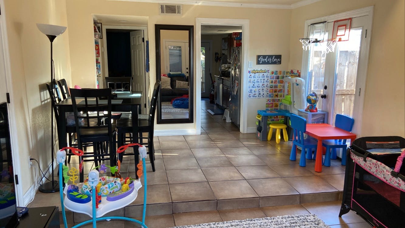 Dining area with black table and chairs, baby jumper, and child's play area