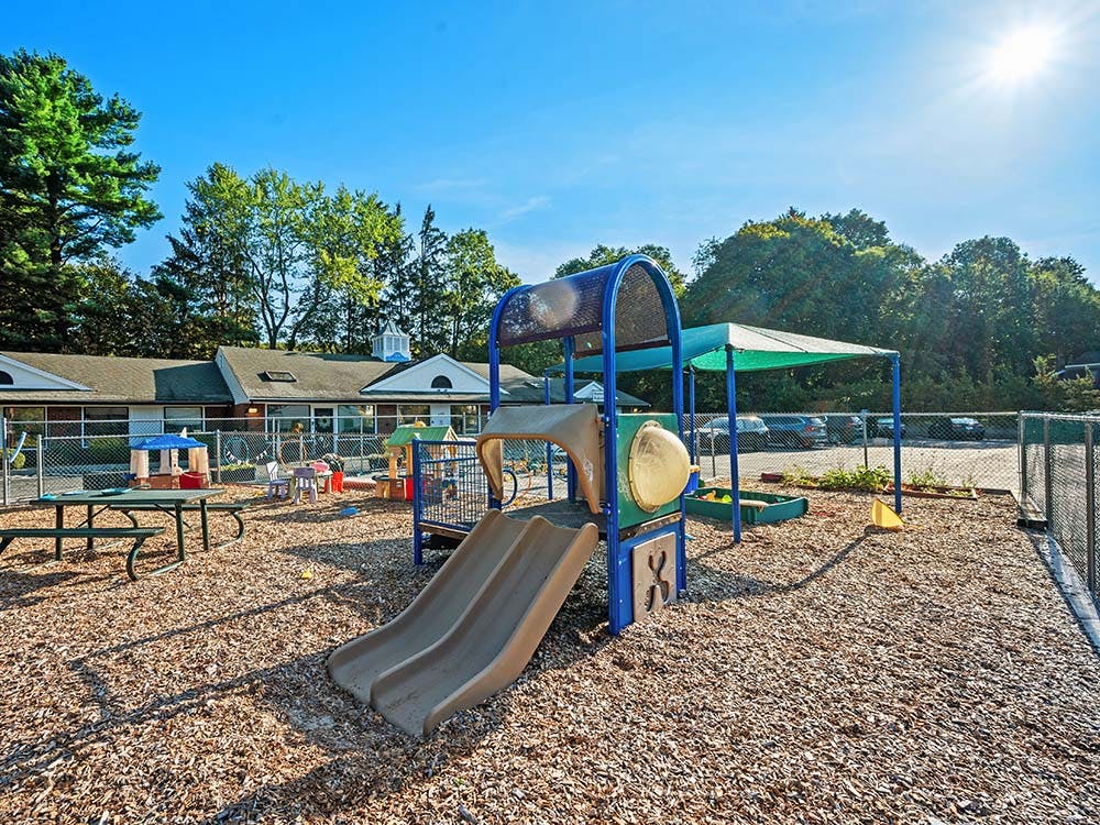 Playground with slides, picnic table, and sandbox on wood chip surface