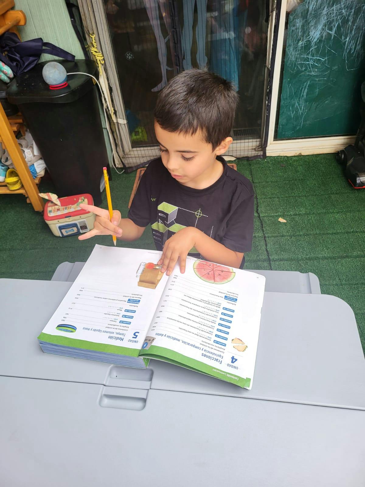 Child holding a pencil and looking at an open book