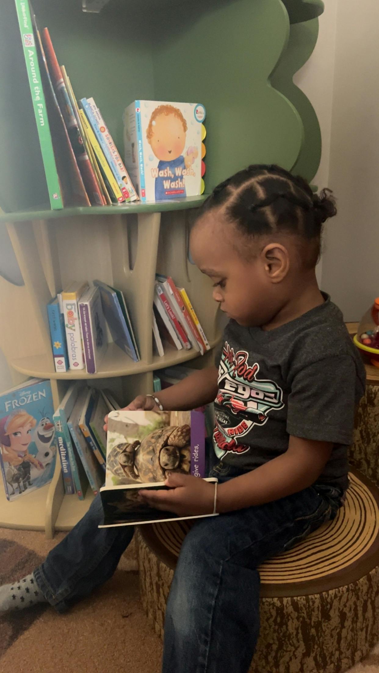 Child sitting on a stool and looking at a book