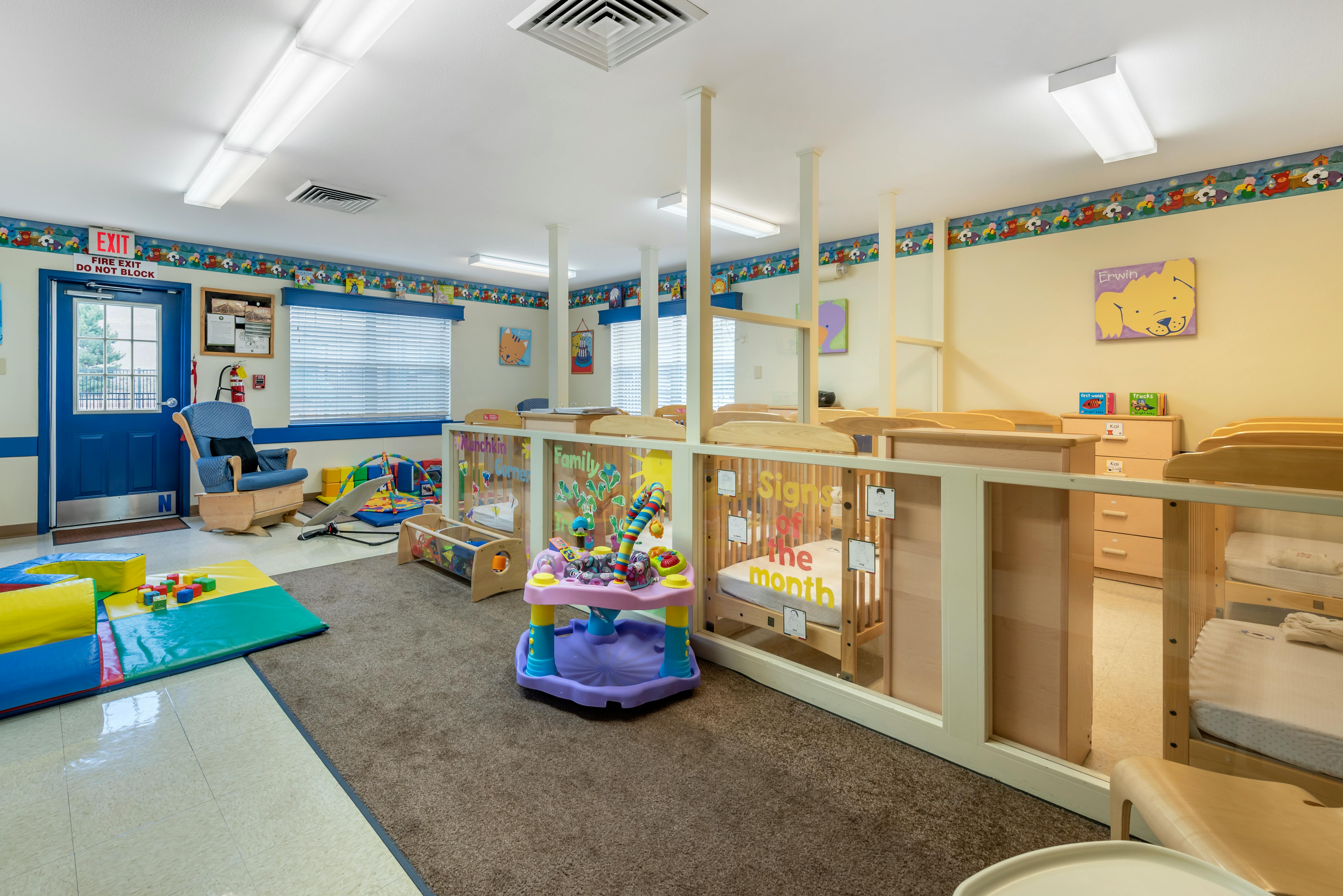 A colorful play area for young children inside a classroom with a blue door