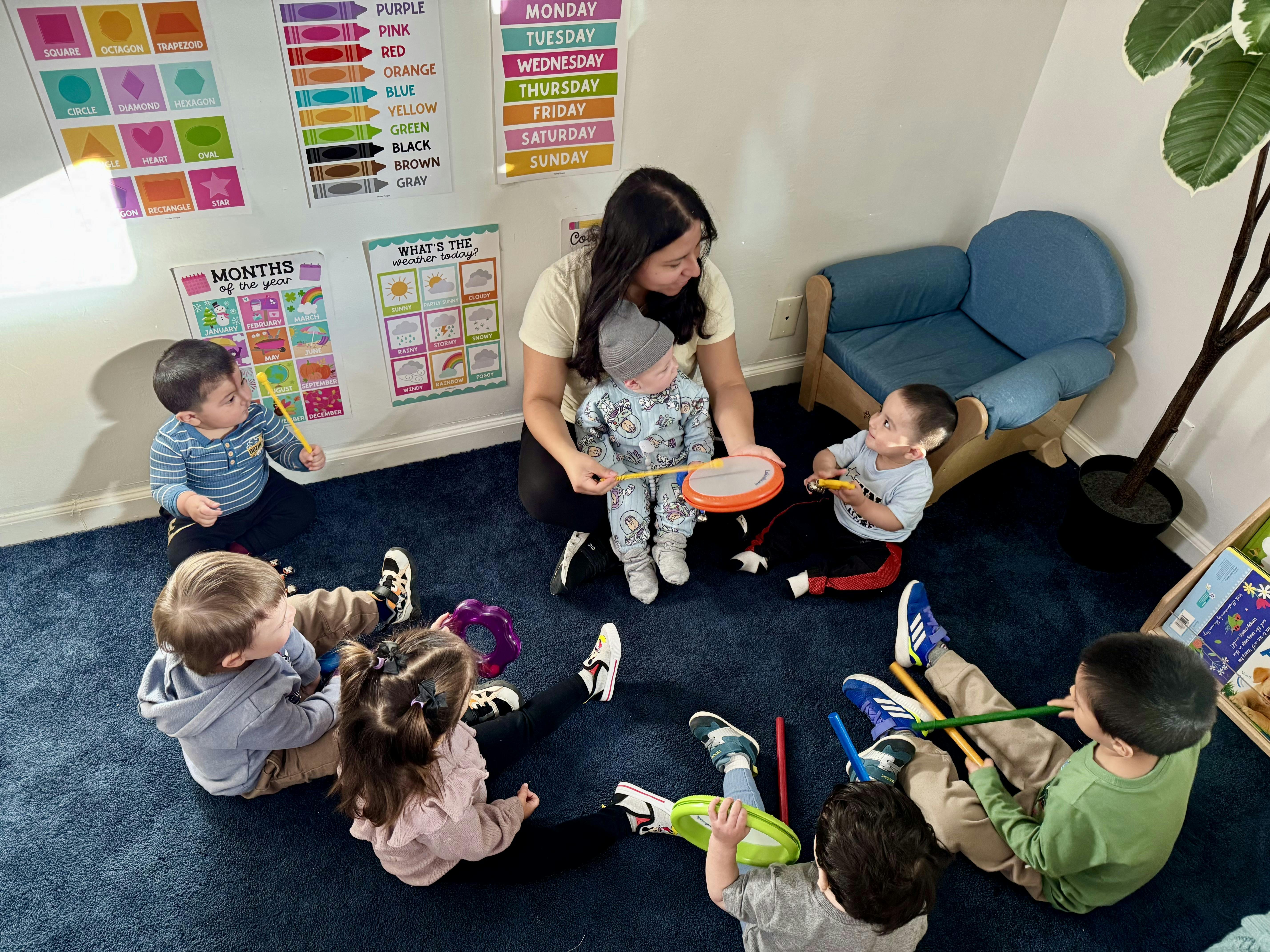 Adult and several children playing with musical instruments on a blue rug