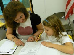 Adult and child writing on paper at a table