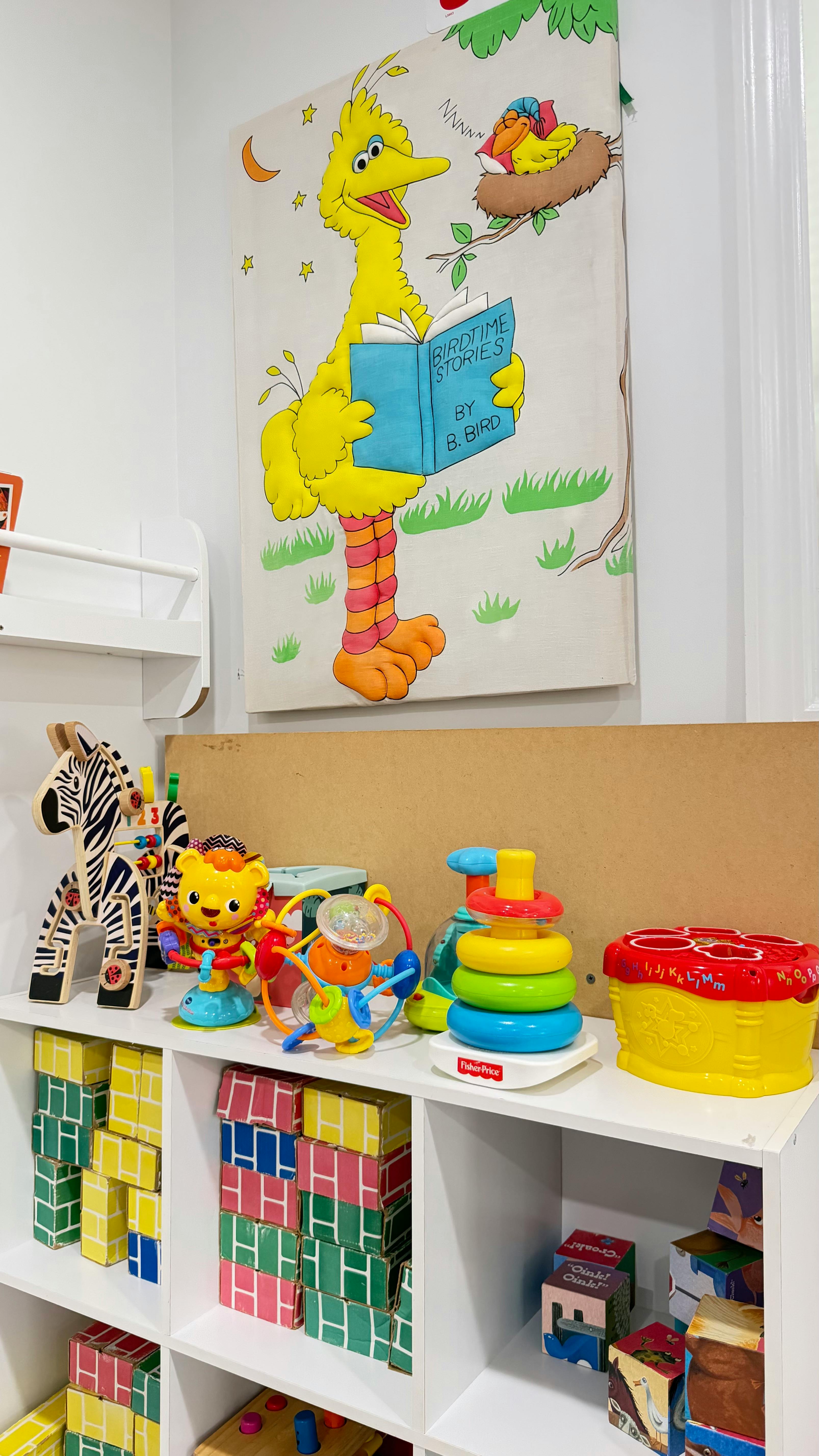 Colorful educational toys displayed on shelves below a mural of a large yellow bird