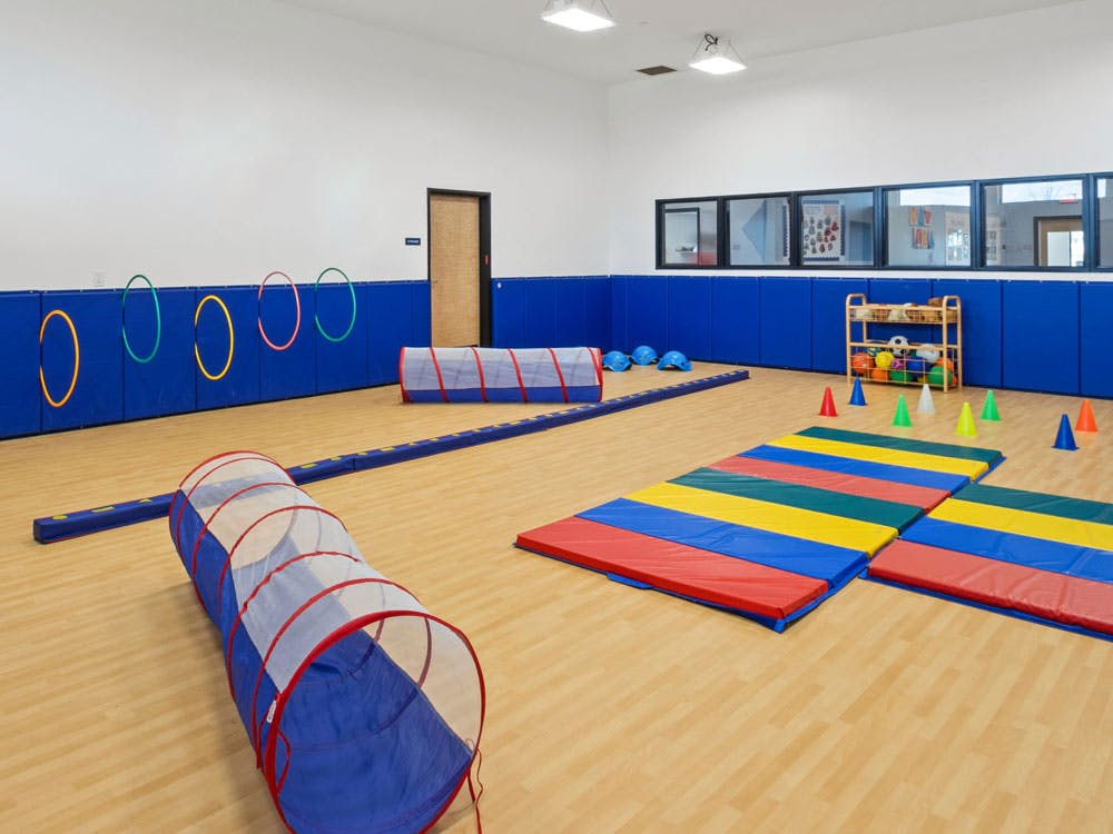 Indoor playroom with tunnels, hoops, mats, and cones