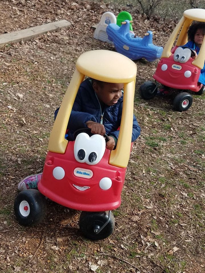 Child in a red toy car