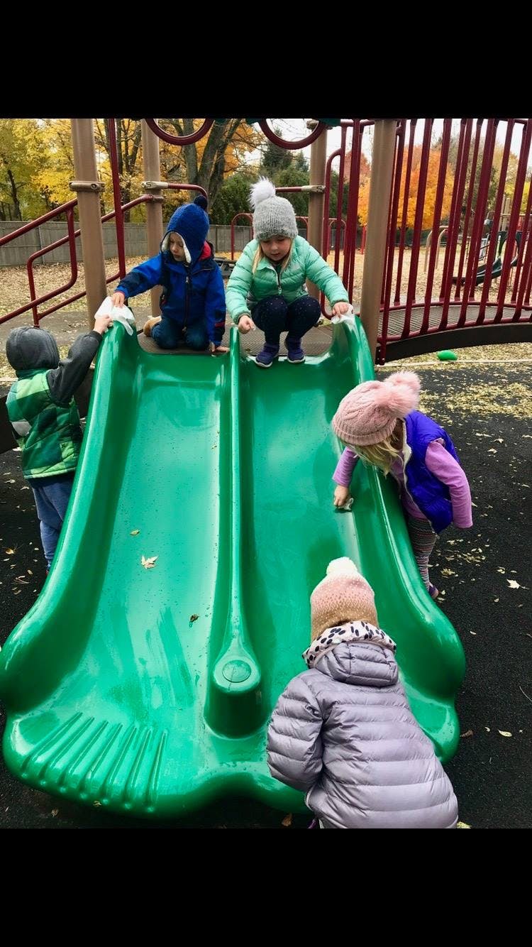 Children playing on a green slide at a playground